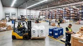 Forklift moving bulk bags and drums in a warehouse