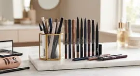 Row of liner pencils and cosmetic tools on a counter
